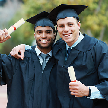 Two male graduates hugging holding diplomas
