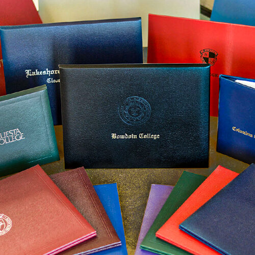 Assorted custom diploma covers with college logos and embossed seals — Paradigm’s premium graduation credential presentation solutions.